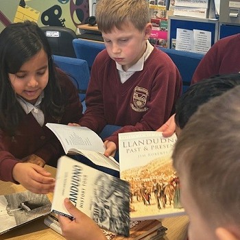 children year 3 to 6 reading historical books on Llandudno