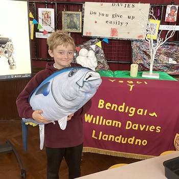 myfyriwr yn dal tegan meddal pysgodyn