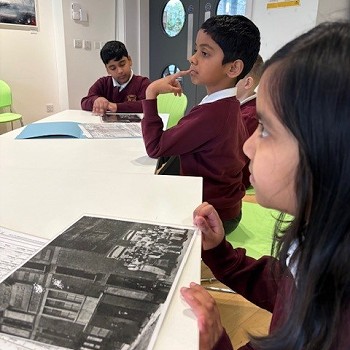 children sitting around a white desk and looking at old images