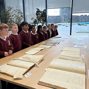 children stinging by a table full ond old books, census and photosgraphs