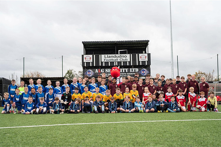 Plant yn chwarae ar gae pêl-droed Clwb Pêl-droed Llandudno