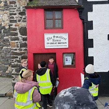 disgyblion yn sefyll y tu allan i'r tŷ lleiaf yng Nghonwy