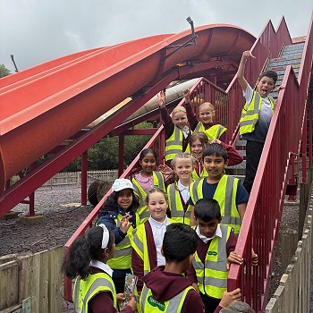 students in hivis walking up the stairs to a slide