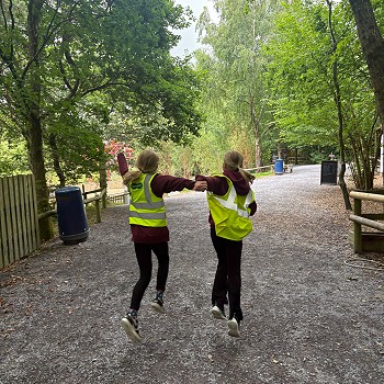 2 students running throuuh the woods