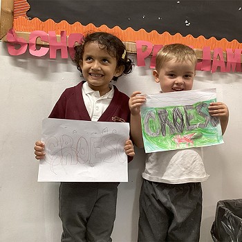 Two children holding a poster they've drawn with the word Croeso
