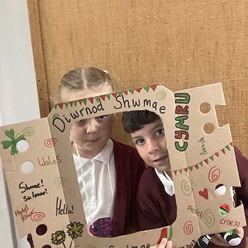 A boy and girl holding a poster that says Diwrnod Shwmae